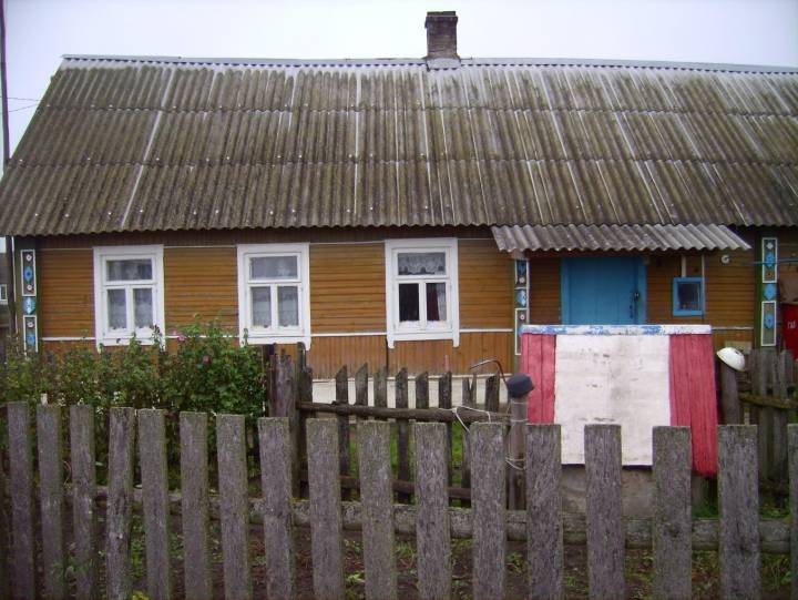 Chata z ozdobnymi zewnętrznymi elementami na początku wioski.